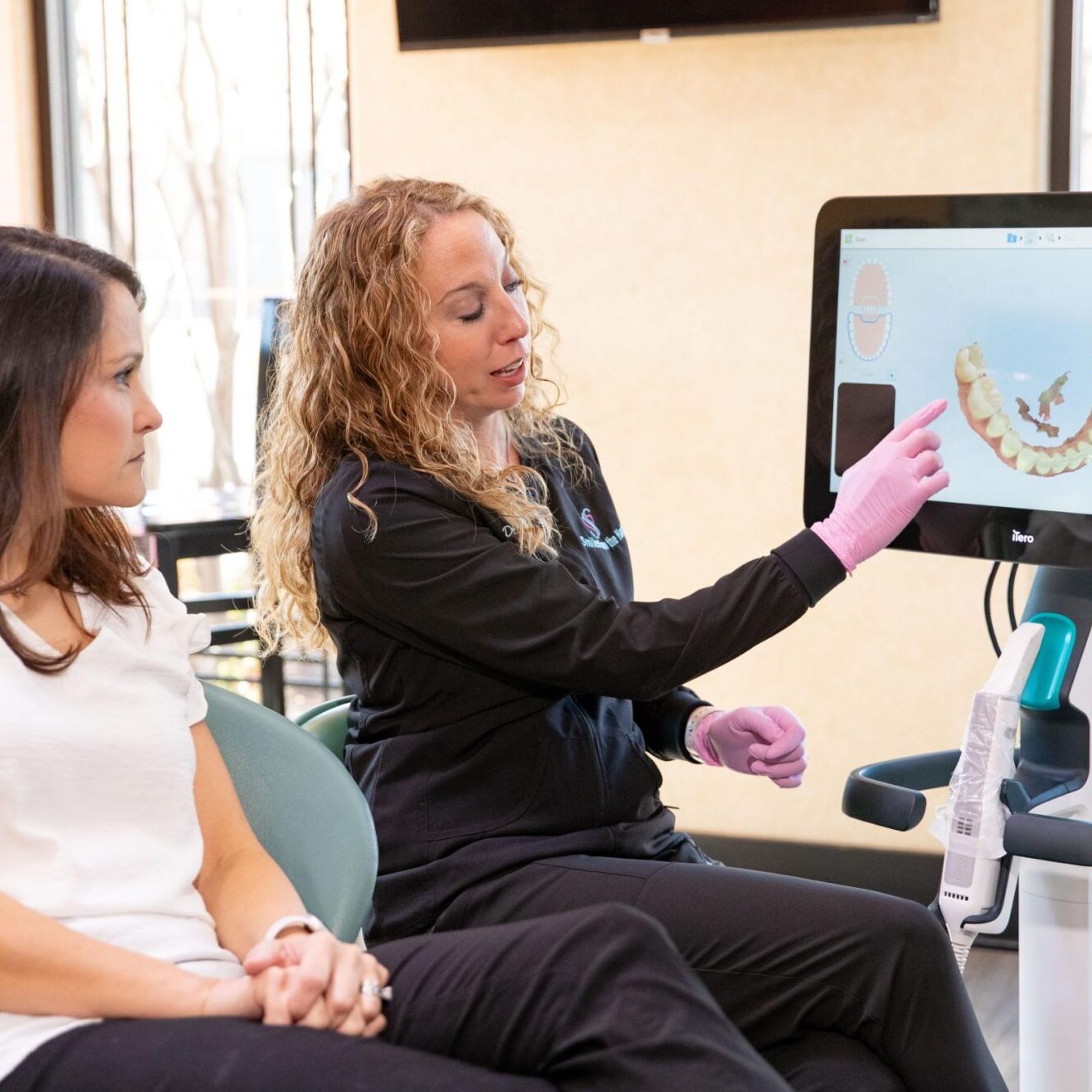 Dental professional explaining orthodontic treatment options to a patient using a digital display in a welcoming clinic setting.
