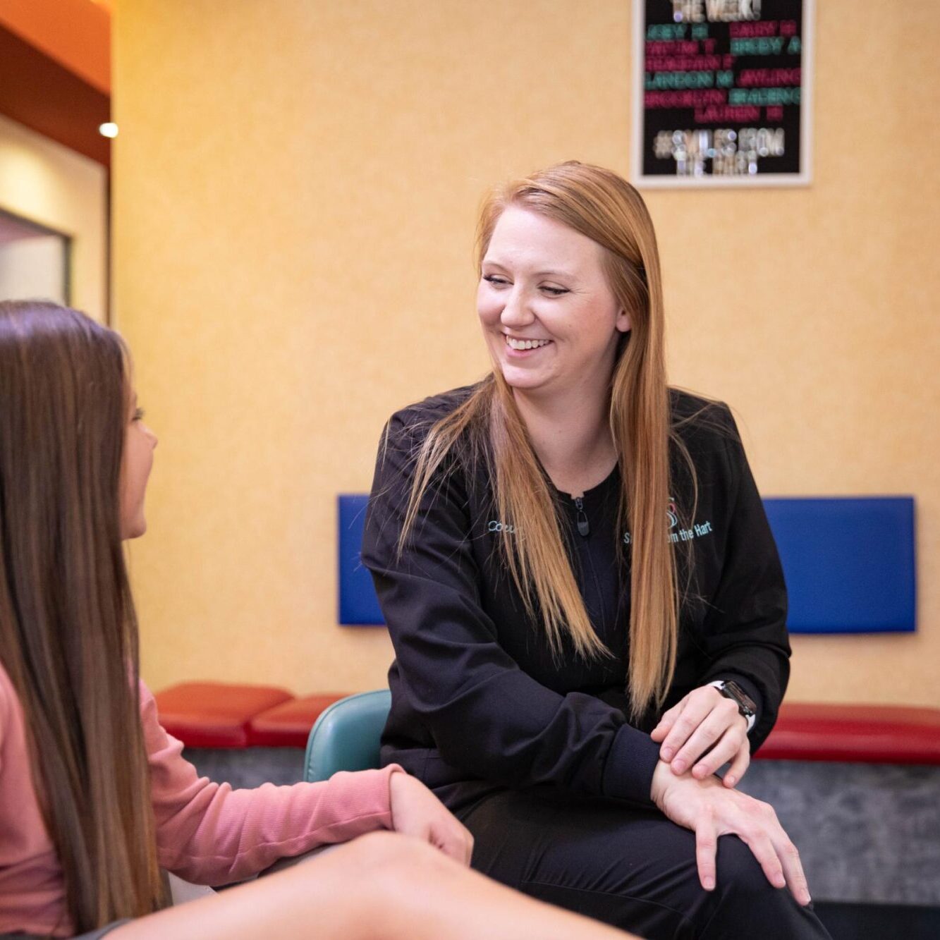 Orthodontist interacting with a young patient in a welcoming office setting at Smiles from the Hart, emphasizing personalized care and comfort for new patients.